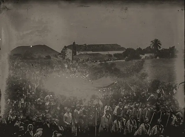 Procesión del Corpus subiendo por La Calzada, con las ramas de fayas adornadas con pañuelos y el templo de San Blas al fondo. Colección Rosendo Cutillas, Archivo General de La Palma. Primeros años del siglo XX.