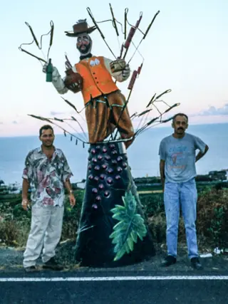 Una de las figuras que acompañan al Borrachito, con sus creadores.